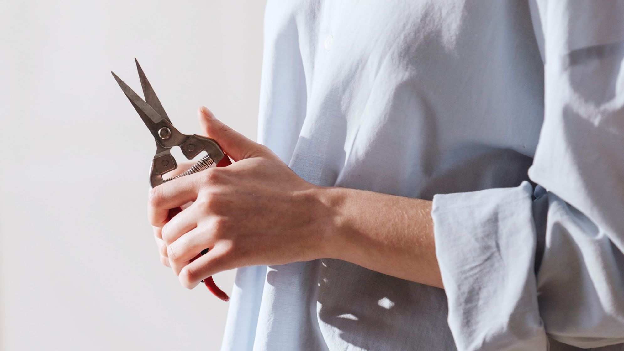 Close-up of a woman holds a pair of red secateurs