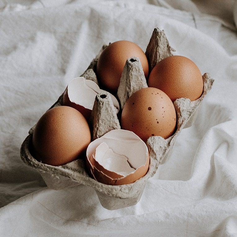 A carton of eggshells on a white tablecloth