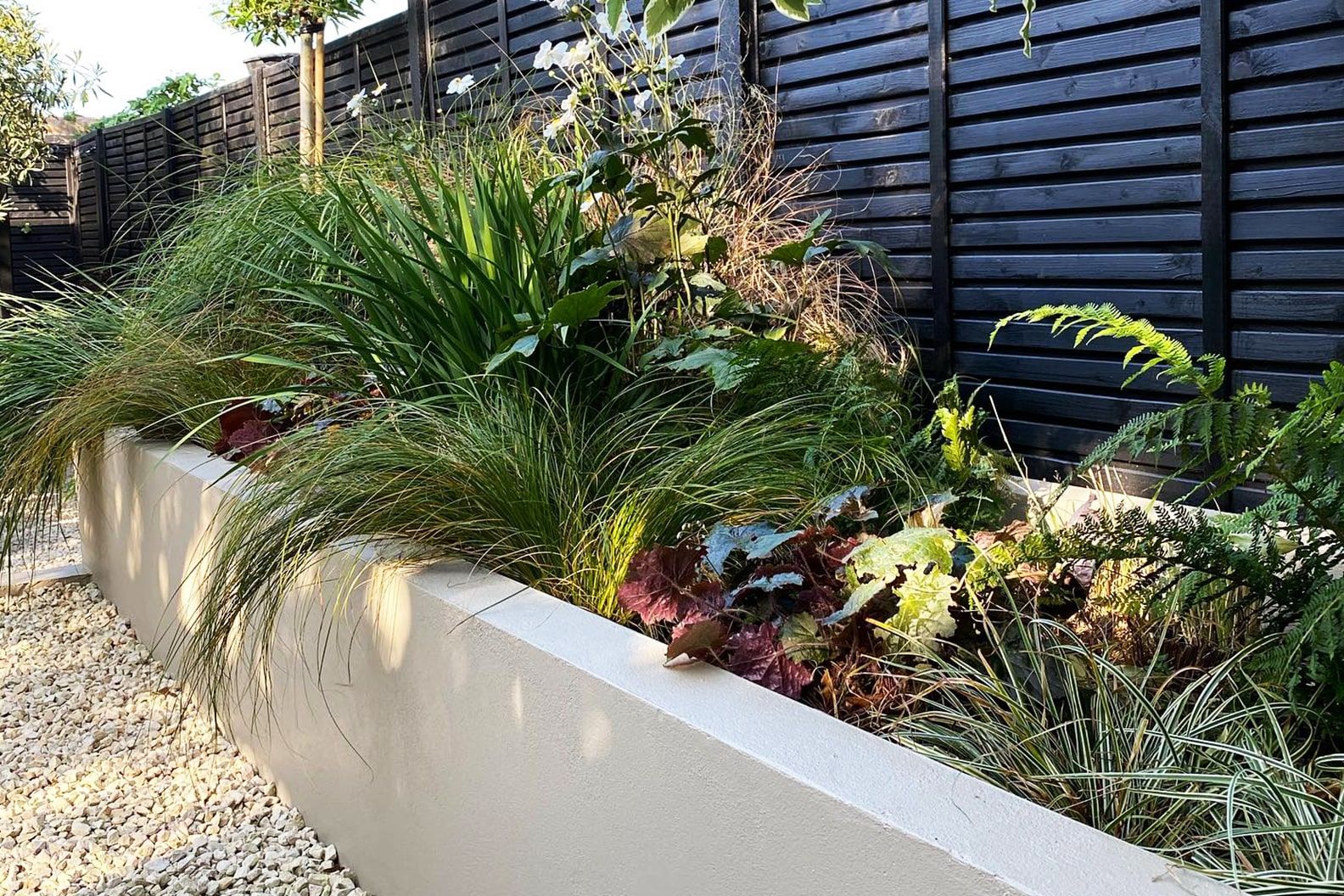 A wall planter filled with grasses and ferns.