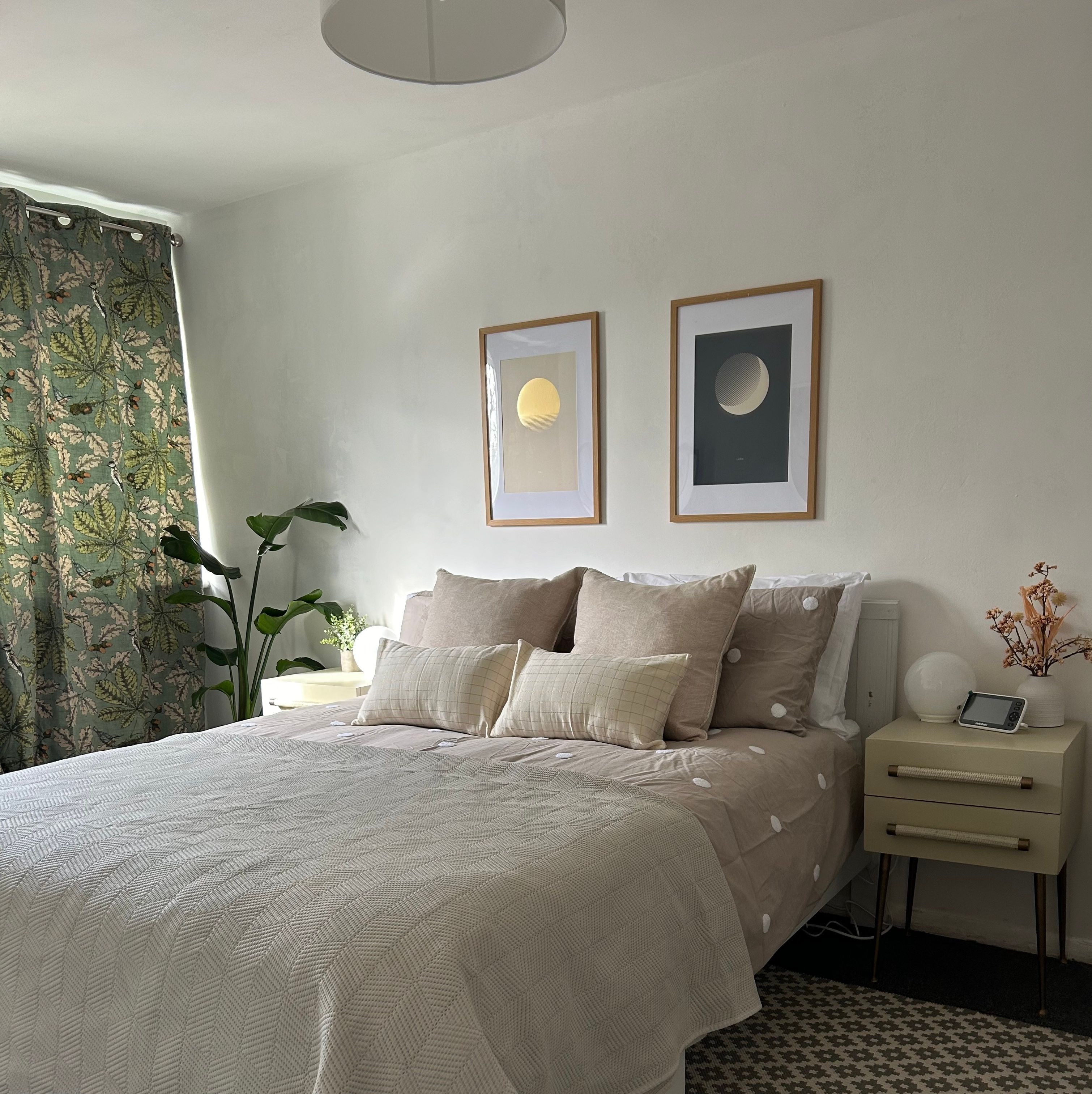 A bedroom with green curtains, plants and a bed with soft furnishings